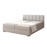 Világosszürke boxspring ágy beépített matraccal.